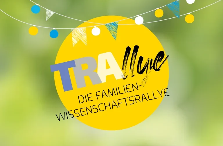 Eine Wissenschaftlerin und ein Wissenschaftler arbeiten hinter einer Glasfassade und mischen Chemikalien mit Großgeräten.
