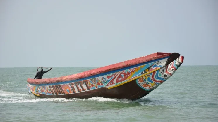 Eine Wissenschaftlerin und ein Wissenschaftler arbeiten hinter einer Glasfassade und mischen Chemikalien mit Großgeräten.